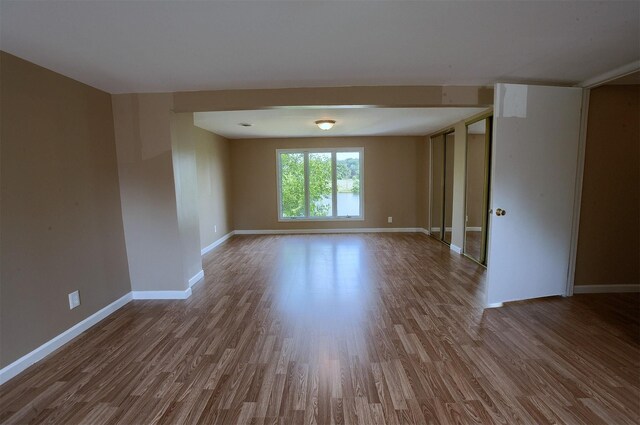 spare room featuring baseboards and wood finished floors