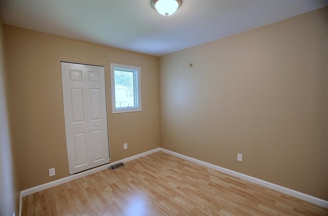 unfurnished room featuring visible vents, light wood-type flooring, and baseboards