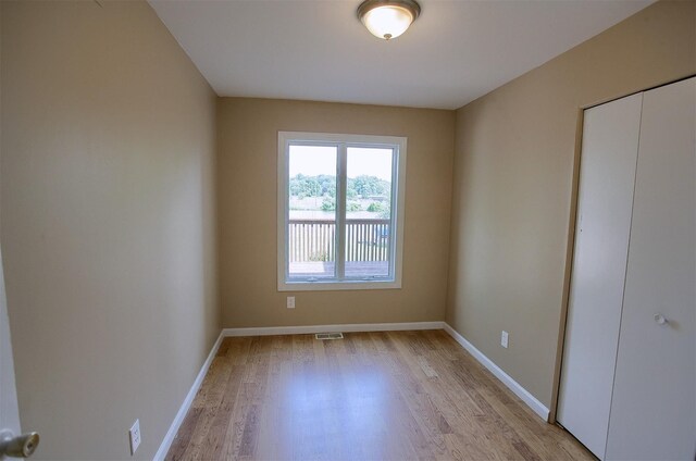 unfurnished bedroom featuring light wood-type flooring, baseboards, visible vents, and a closet