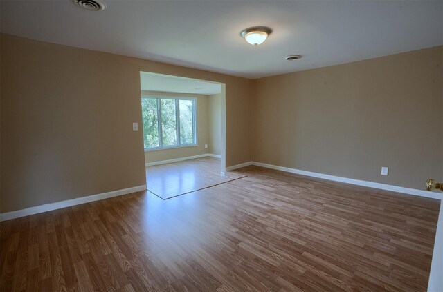 empty room with visible vents, baseboards, and wood finished floors