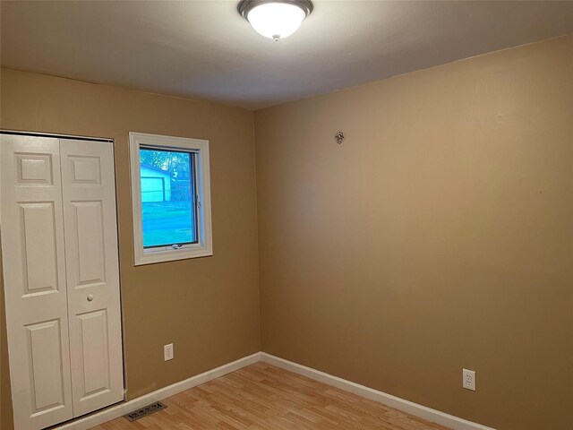 unfurnished bedroom featuring visible vents, baseboards, light wood-style floors, and a closet