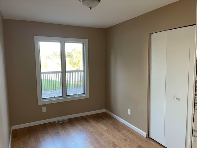 unfurnished bedroom with a closet, visible vents, light wood-type flooring, and baseboards