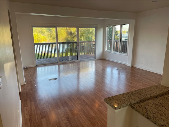 empty room with visible vents, baseboards, and wood finished floors