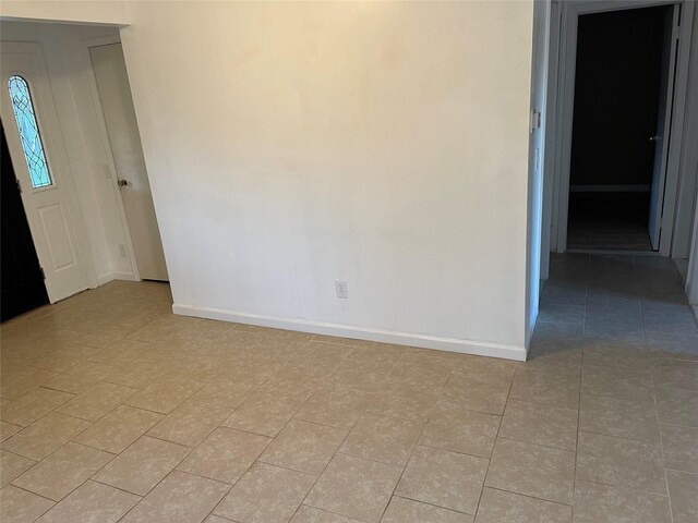 spare room featuring light tile patterned flooring and baseboards