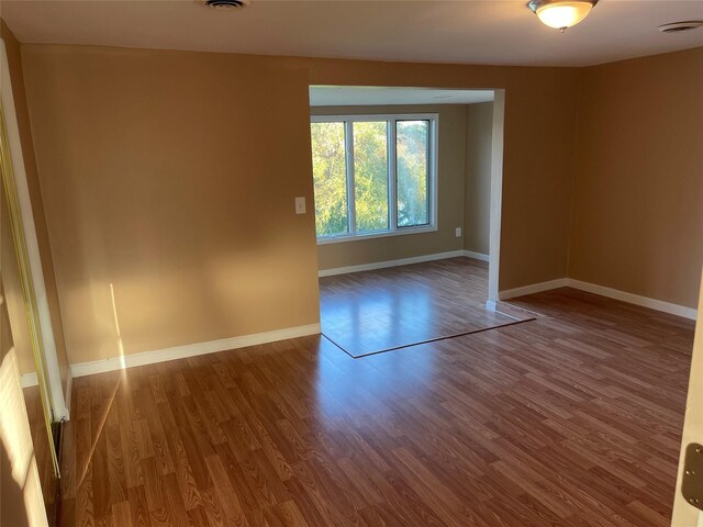 unfurnished room featuring visible vents, baseboards, and wood finished floors