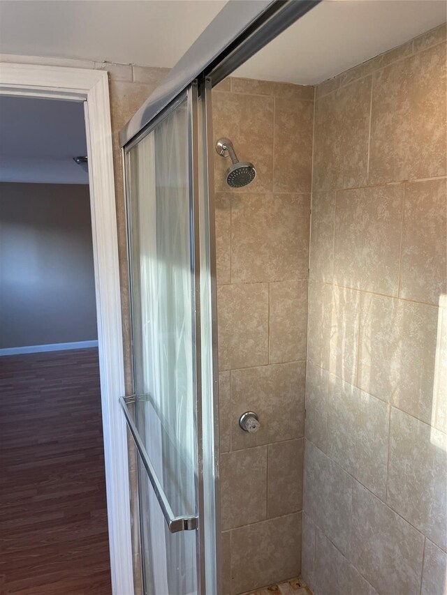 full bathroom with a stall shower and wood finished floors