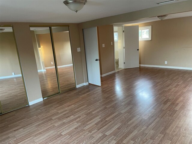 unfurnished bedroom featuring visible vents, wood finished floors, baseboards, and two closets