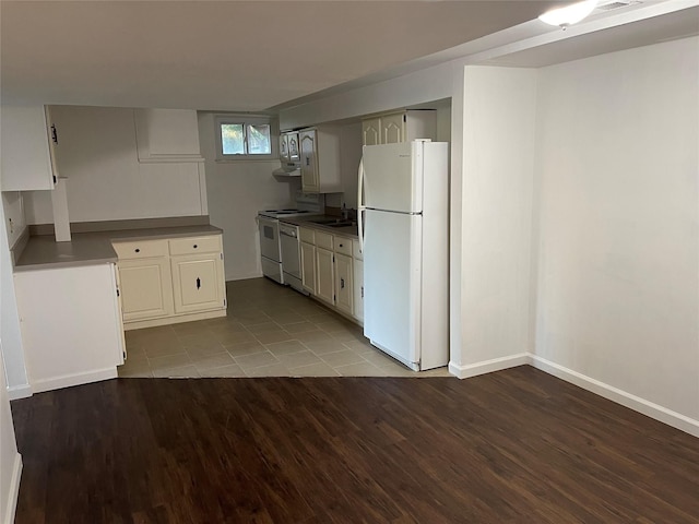 kitchen with baseboards, under cabinet range hood, wood finished floors, white appliances, and a sink