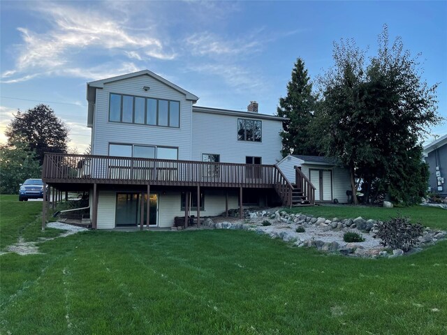 back of property featuring a deck, a chimney, and a yard