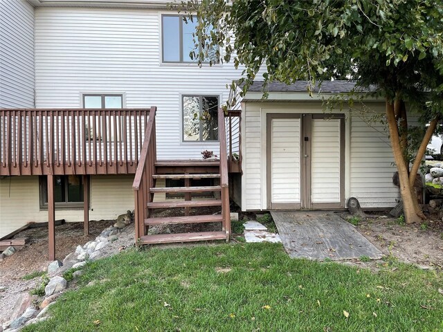 view of exterior entry featuring a deck and a lawn