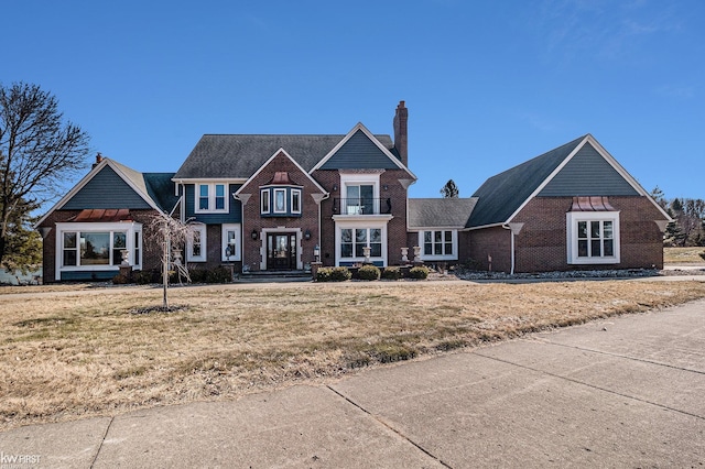 view of front of house featuring brick siding, a chimney, and a front lawn