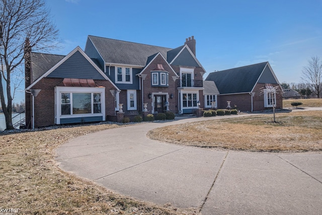 view of front facade featuring concrete driveway, brick siding, and a chimney