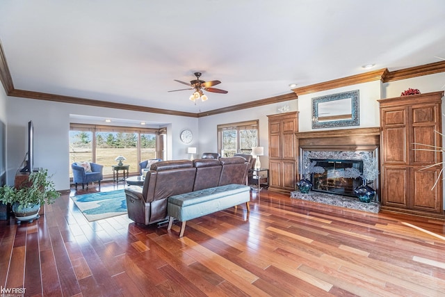 living room featuring a fireplace, crown molding, ceiling fan, and wood finished floors