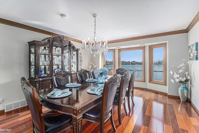 dining space featuring visible vents, crown molding, baseboards, wood finished floors, and a notable chandelier