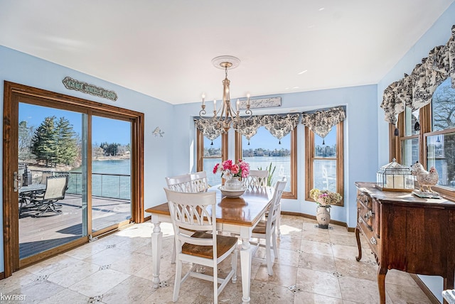 dining area with baseboards, an inviting chandelier, and a water view