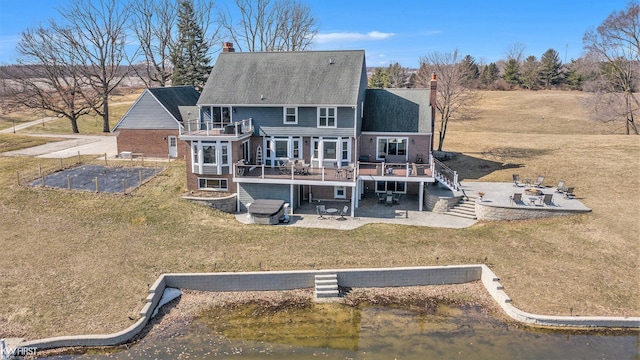 back of house with stairs, a patio, a lawn, and a chimney