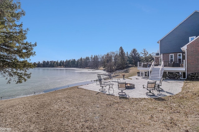 view of yard featuring a patio area, stairway, an outdoor fire pit, and a deck with water view