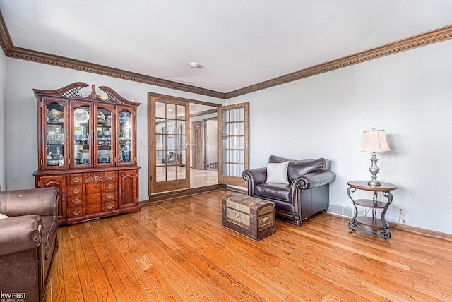 living room featuring light wood finished floors, french doors, crown molding, and baseboards