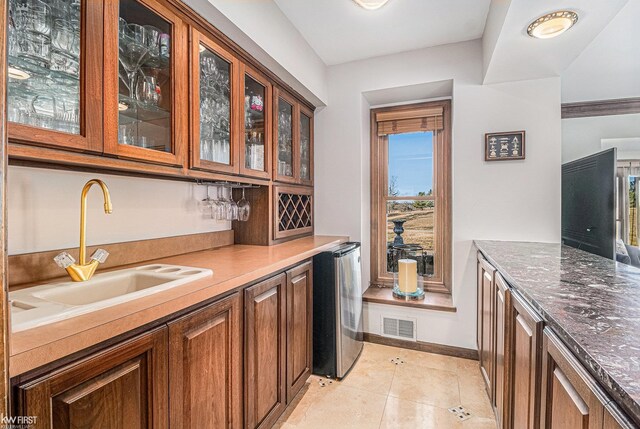 bar with light tile patterned floors, baseboards, visible vents, wet bar, and a sink