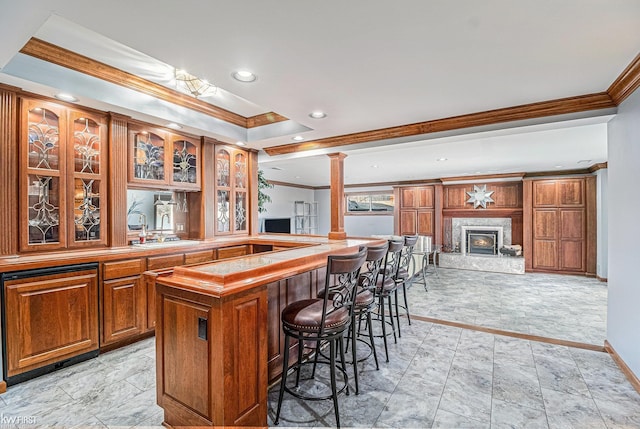 bar featuring recessed lighting, a fireplace, crown molding, and ornate columns