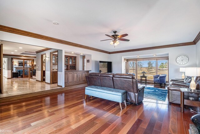 living area with a ceiling fan, crown molding, and wood finished floors