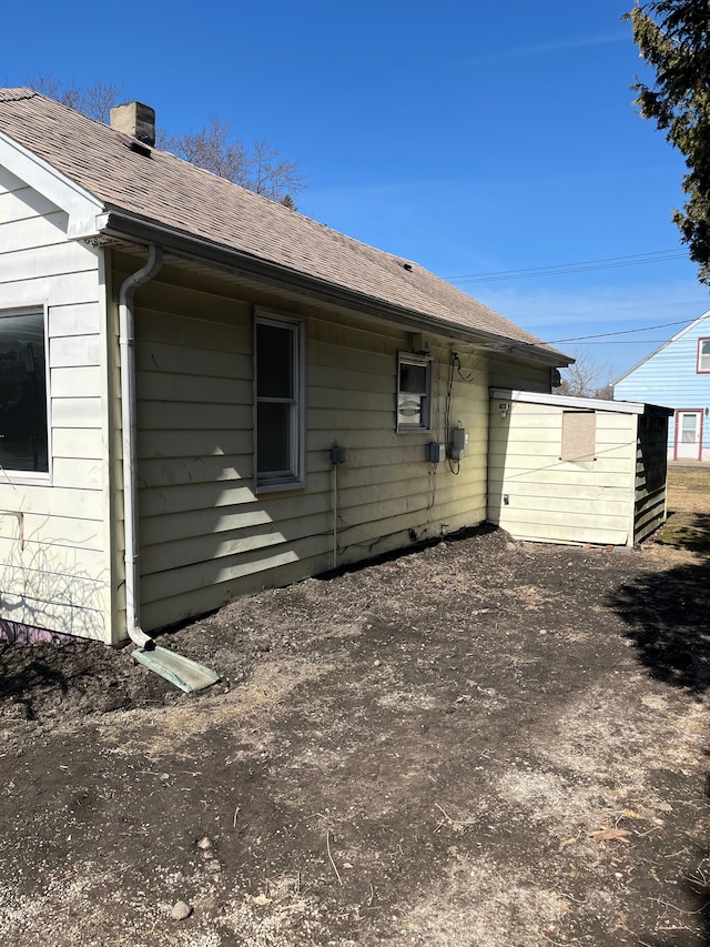 back of property with roof with shingles and a chimney