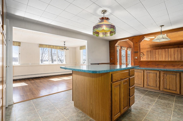 kitchen with decorative light fixtures, wooden walls, brown cabinets, and baseboard heating