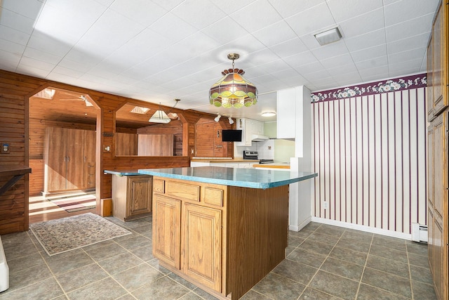 kitchen with hanging light fixtures, wood walls, baseboard heating, and a center island