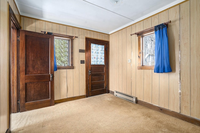 carpeted entryway with wooden walls, a healthy amount of sunlight, and a baseboard radiator