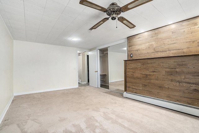 carpeted spare room featuring a baseboard heating unit, baseboards, a ceiling fan, and a baseboard radiator