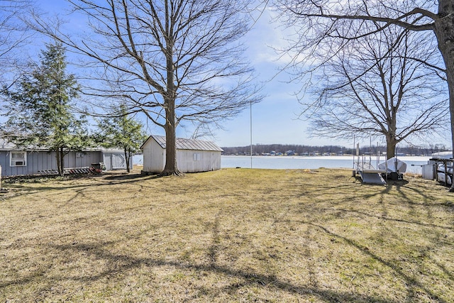 view of yard with an outbuilding, a shed, and a water view