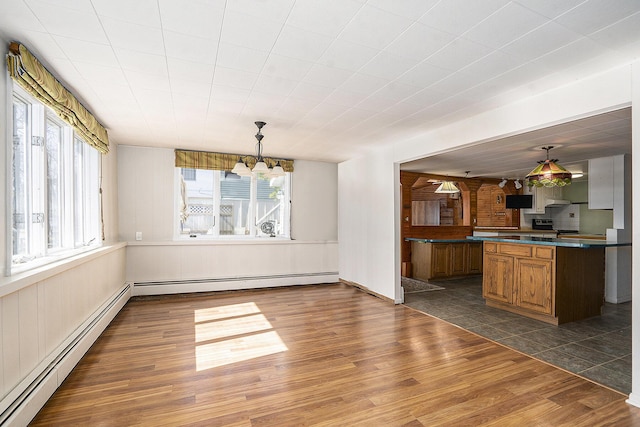 unfurnished dining area with a baseboard radiator, a chandelier, and dark wood-style flooring