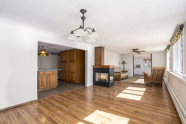 unfurnished living room with dark wood-style floors, a multi sided fireplace, a ceiling fan, and a baseboard radiator