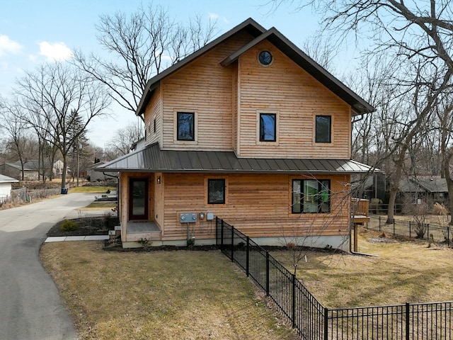 chalet / cabin featuring metal roof, a standing seam roof, a front yard, and fence