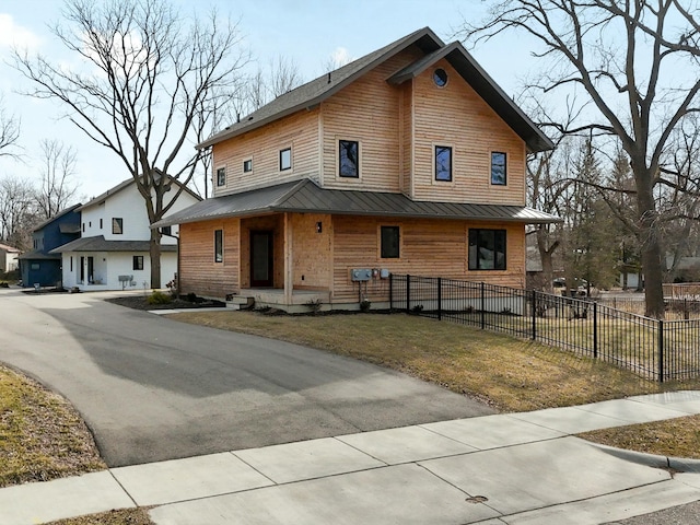 view of front of house featuring metal roof, a standing seam roof, a front lawn, and fence