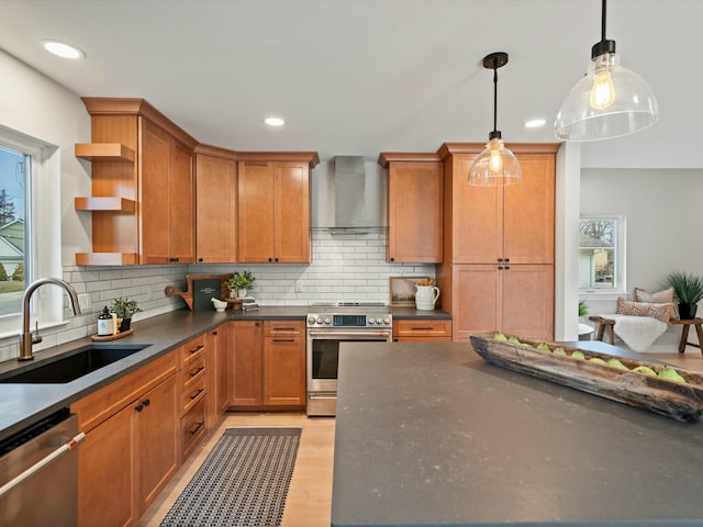 kitchen with decorative backsplash, appliances with stainless steel finishes, wall chimney exhaust hood, and a sink