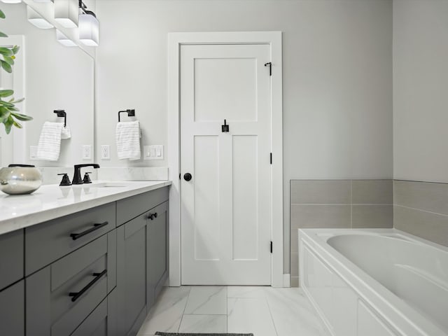 full bathroom featuring vanity, a garden tub, and marble finish floor