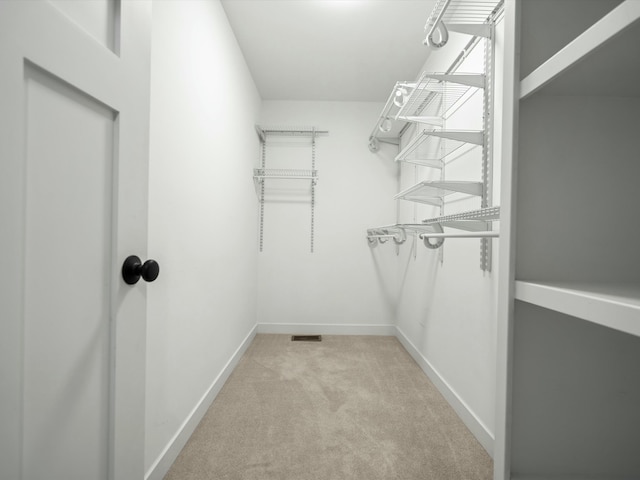 walk in closet featuring light colored carpet