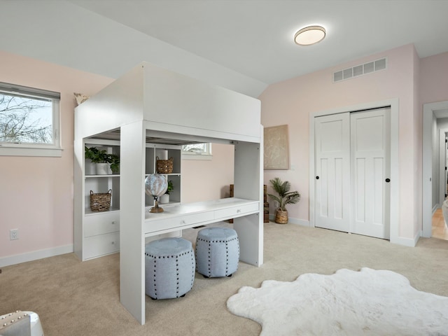 home office featuring lofted ceiling, baseboards, visible vents, and light carpet