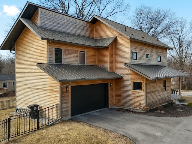 exterior space with fence, roof with shingles, metal roof, a garage, and driveway