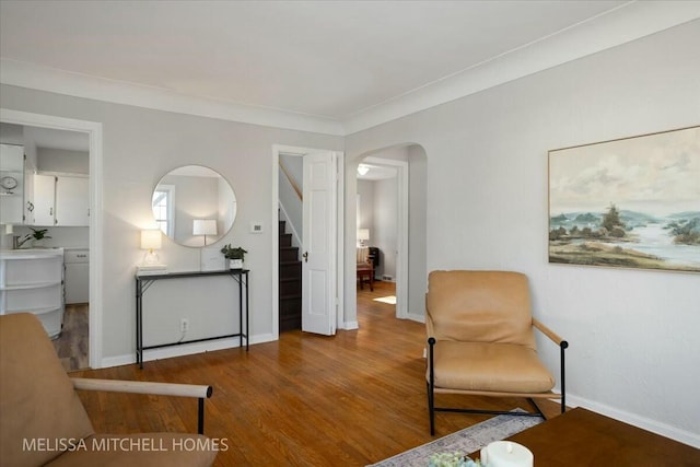 living area featuring wood finished floors, stairway, arched walkways, crown molding, and baseboards