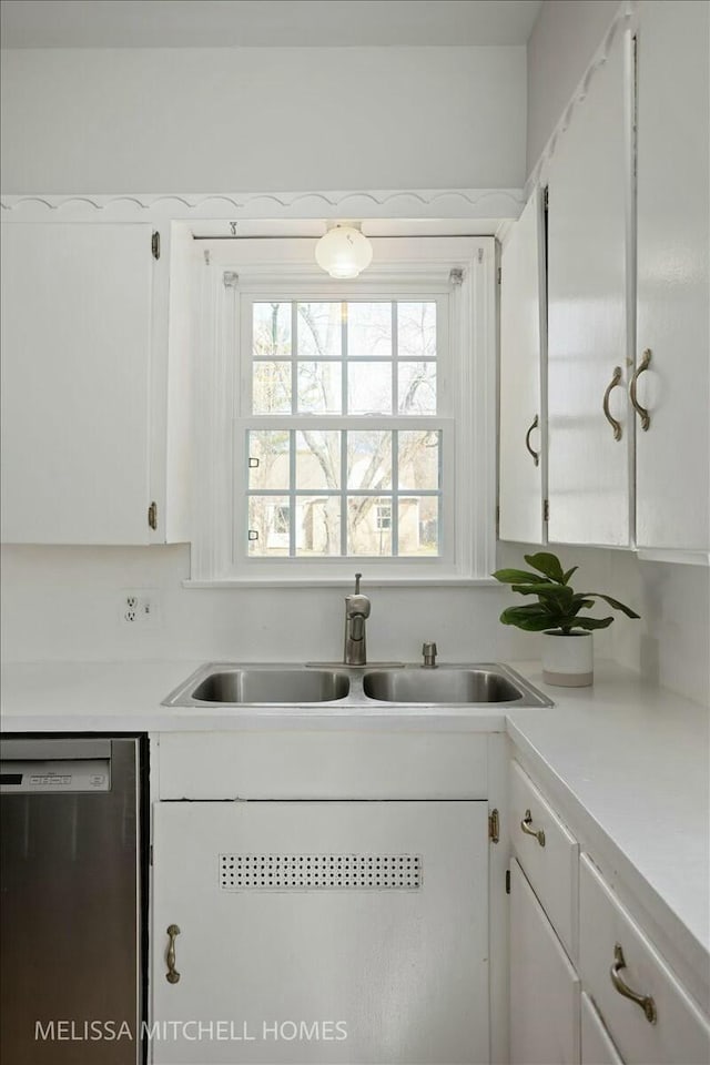 kitchen with white cabinets, dishwasher, light countertops, and a sink