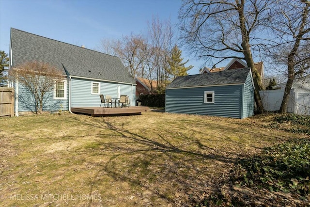 back of property with an outbuilding, a lawn, a deck, and fence