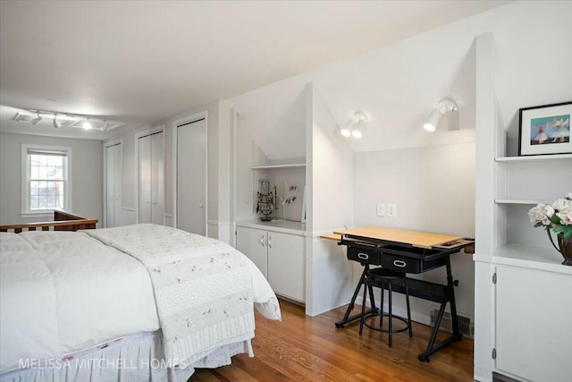 bedroom featuring wood finished floors and two closets