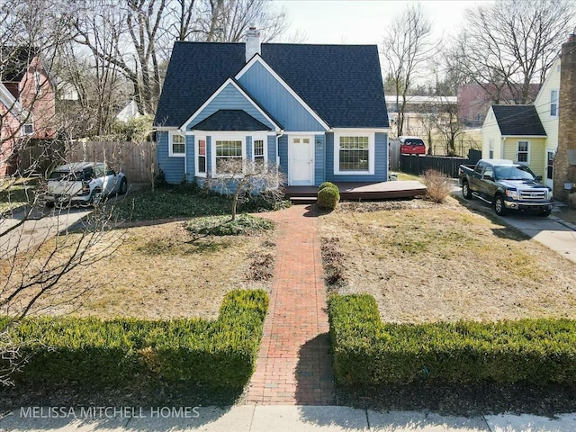 view of front of home with a shingled roof, fence, and a chimney