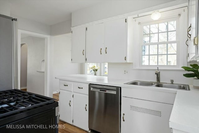 kitchen with black gas stove, dishwasher, light countertops, white cabinetry, and a sink