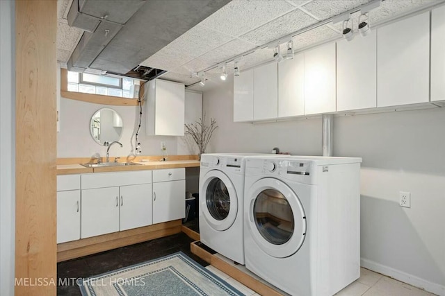 washroom with independent washer and dryer, a sink, cabinet space, rail lighting, and baseboards