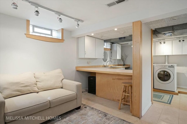 interior space with visible vents, washer / dryer, and track lighting