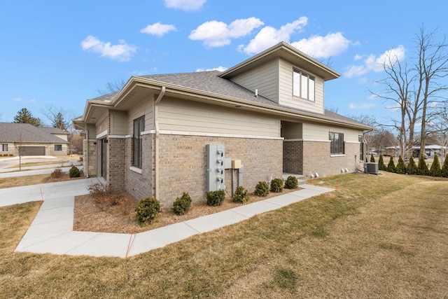 view of property exterior featuring brick siding, a lawn, a shingled roof, and central AC