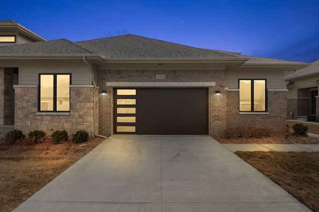 prairie-style house with brick siding, concrete driveway, a shingled roof, and a garage